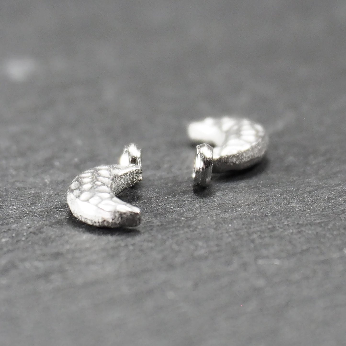 Halbmond-Anhänger, silberfarben metallisch mit gehämmerter, reliefartiger Oberfläche und integrierter Öse oben.