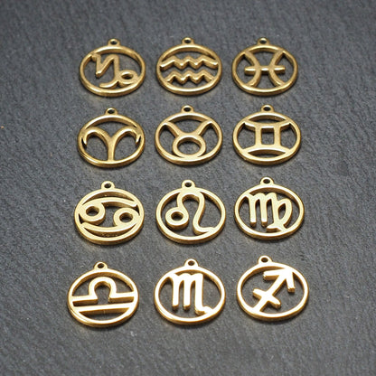 Zwölf goldfarbene, glänzende, runde Anhänger mit durchbrochenen Sternzeichen-Symbolen in feinem Metallrahmen, jeweils mit kleiner Öse oben.