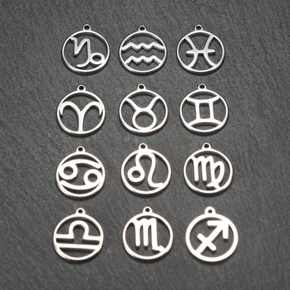 Zwölf runde silberne Anhänger mit durchbrochenen Sternzeichenmotiven, glänzende Oberfläche, integrierte Öse, auf dunklem strukturiertem Untergrund.