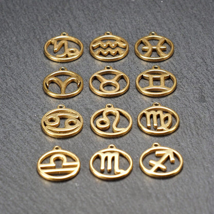 Zwölf goldfarbene, glänzende, runde Anhänger mit durchbrochenen Sternzeichen-Symbolen in feinem Metallrahmen, jeweils mit kleiner Öse oben.