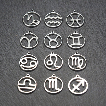 Zwölf runde silberne Anhänger mit durchbrochenen Sternzeichenmotiven, glänzende Oberfläche, integrierte Öse, auf dunklem strukturiertem Untergrund.