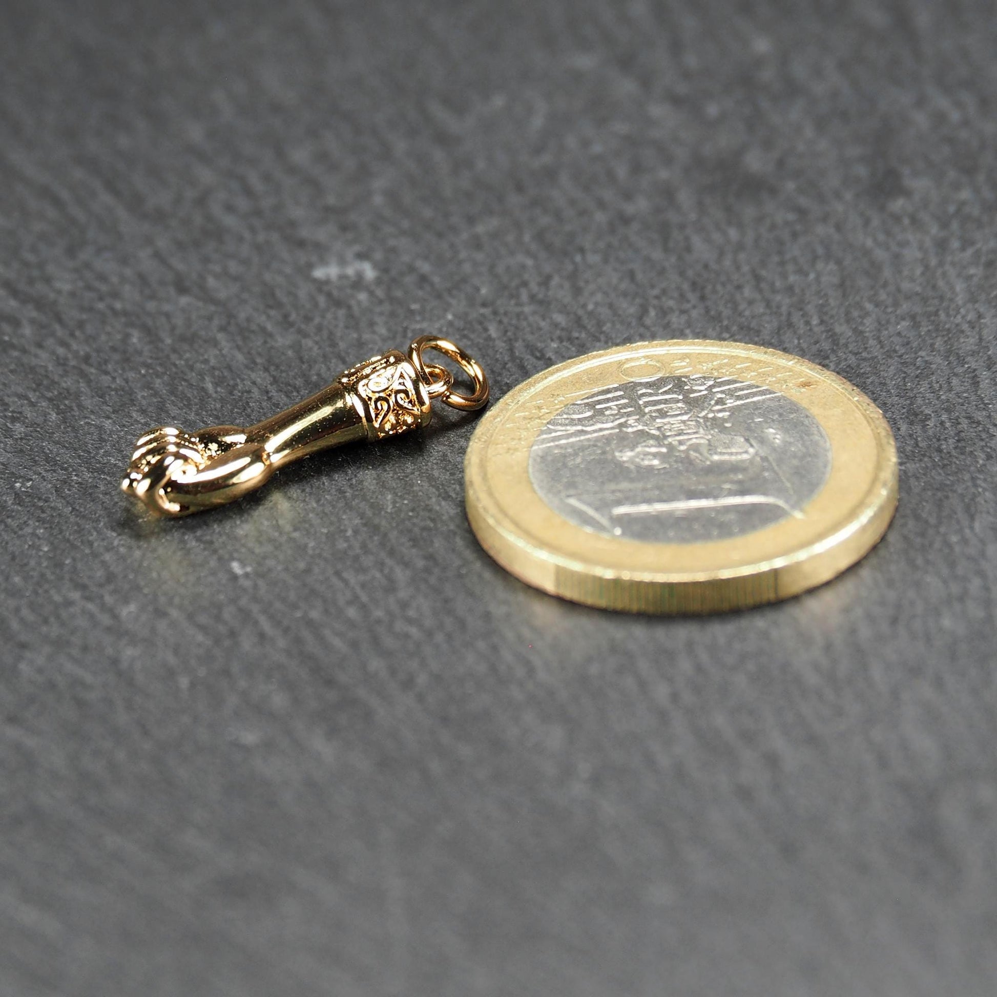 Goldfarbener Anhänger in Figa-Hand-Form mit glänzender Oberfläche, fein gravierter ornamentaler Manschette und kleiner Anhängeröse.