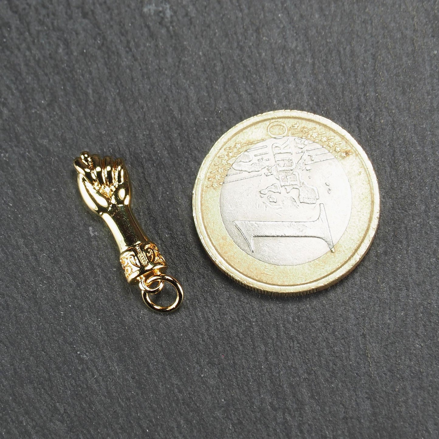 Goldfarbener Anhänger in Figa-Hand-Form mit glänzender Oberfläche, fein gravierter ornamentaler Manschette und kleiner Anhängeröse.