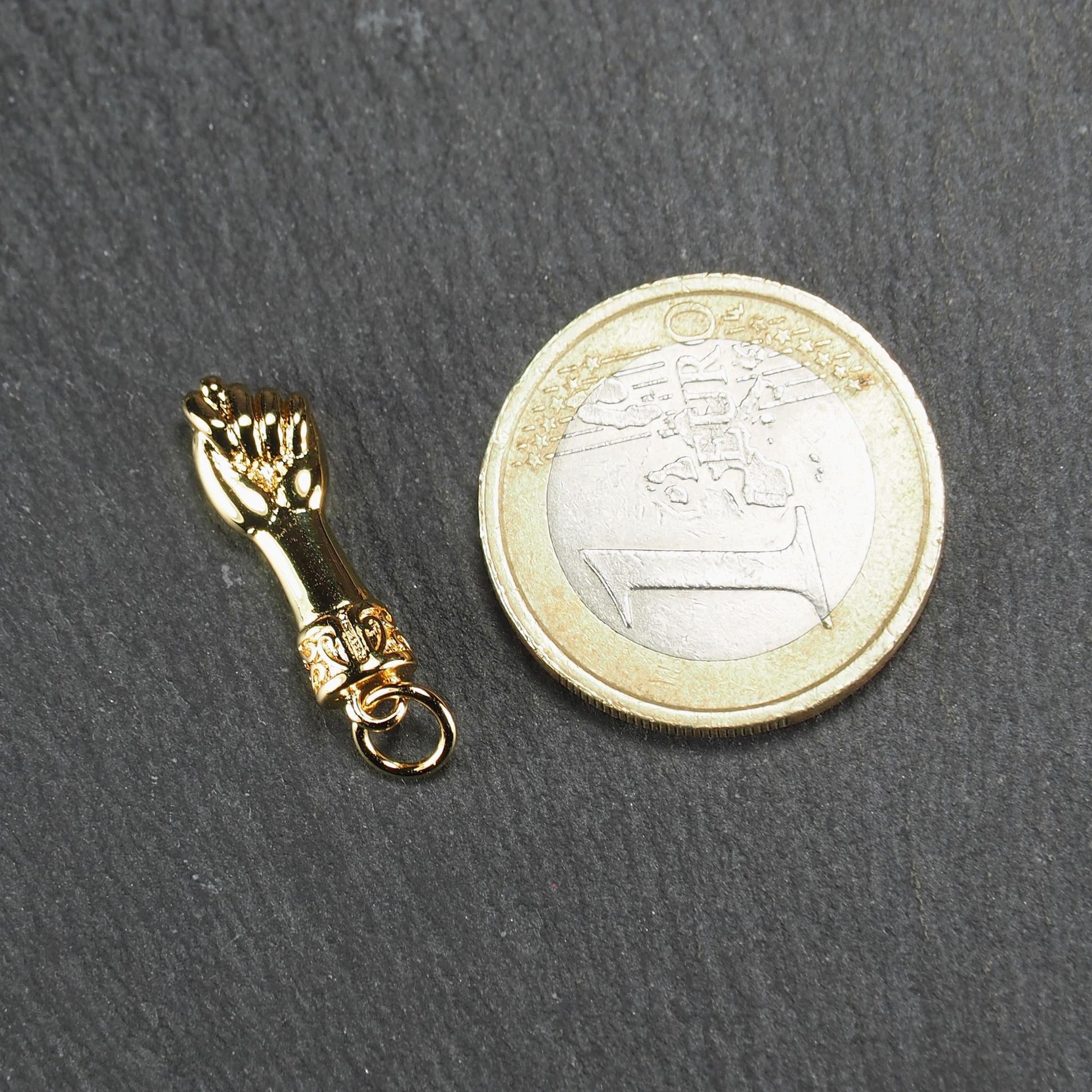 Goldfarbener Anhänger in Figa-Hand-Form mit glänzender Oberfläche, fein gravierter ornamentaler Manschette und kleiner Anhängeröse.