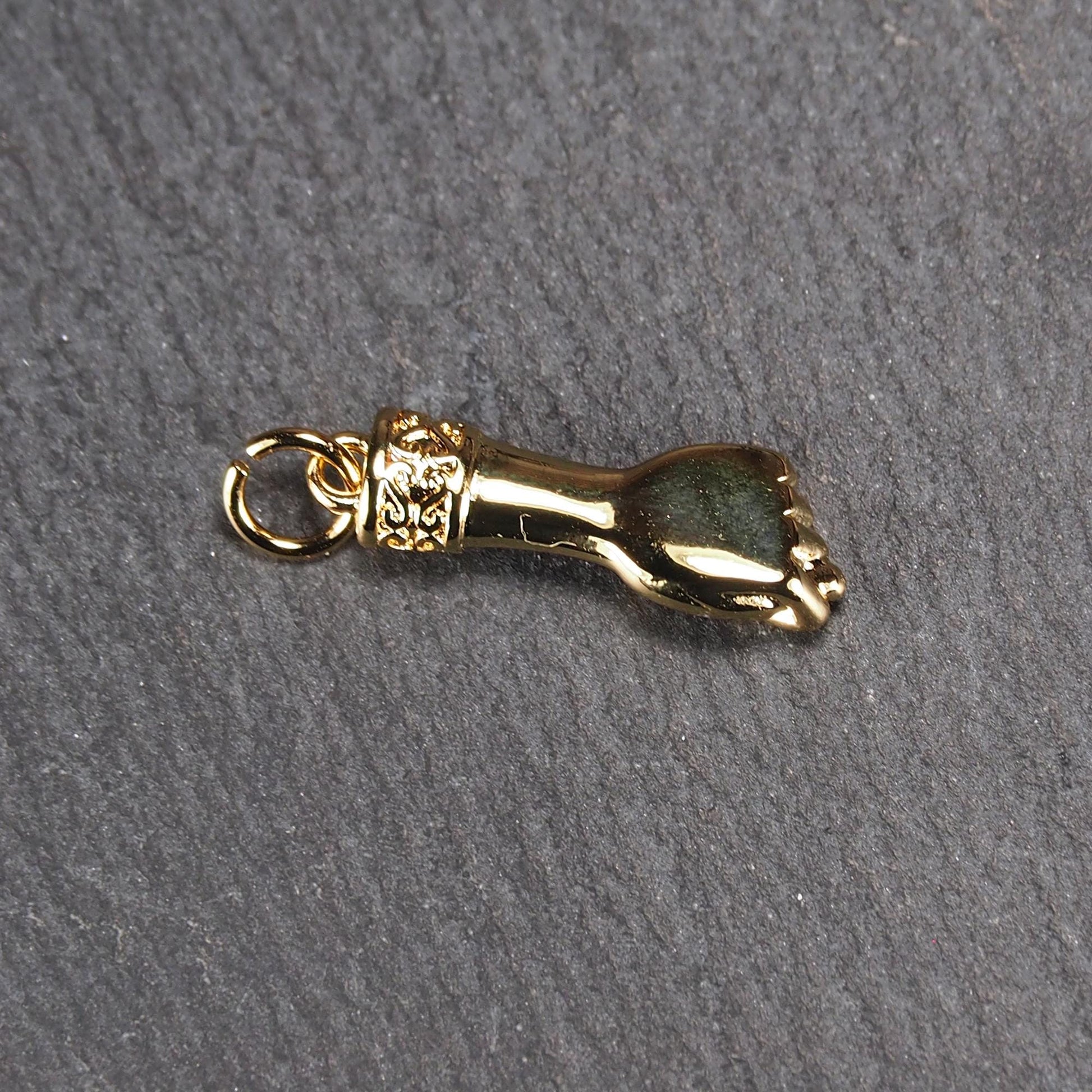 Goldfarbener Anhänger in Figa-Hand-Form mit glänzender Oberfläche, fein gravierter ornamentaler Manschette und kleiner Anhängeröse.