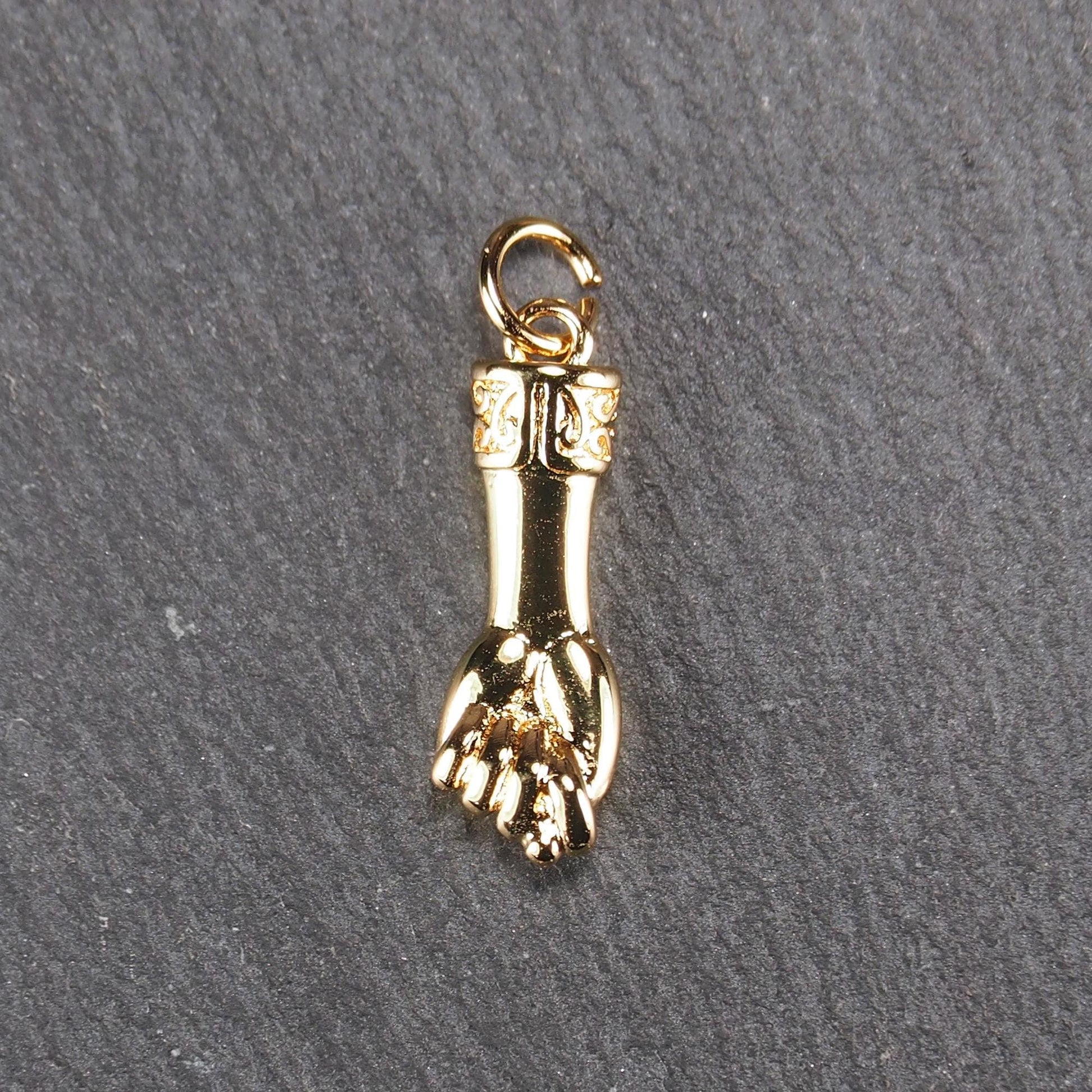 Goldfarbener Anhänger in Figa-Hand-Form mit glänzender Oberfläche, fein gravierter ornamentaler Manschette und kleiner Anhängeröse.