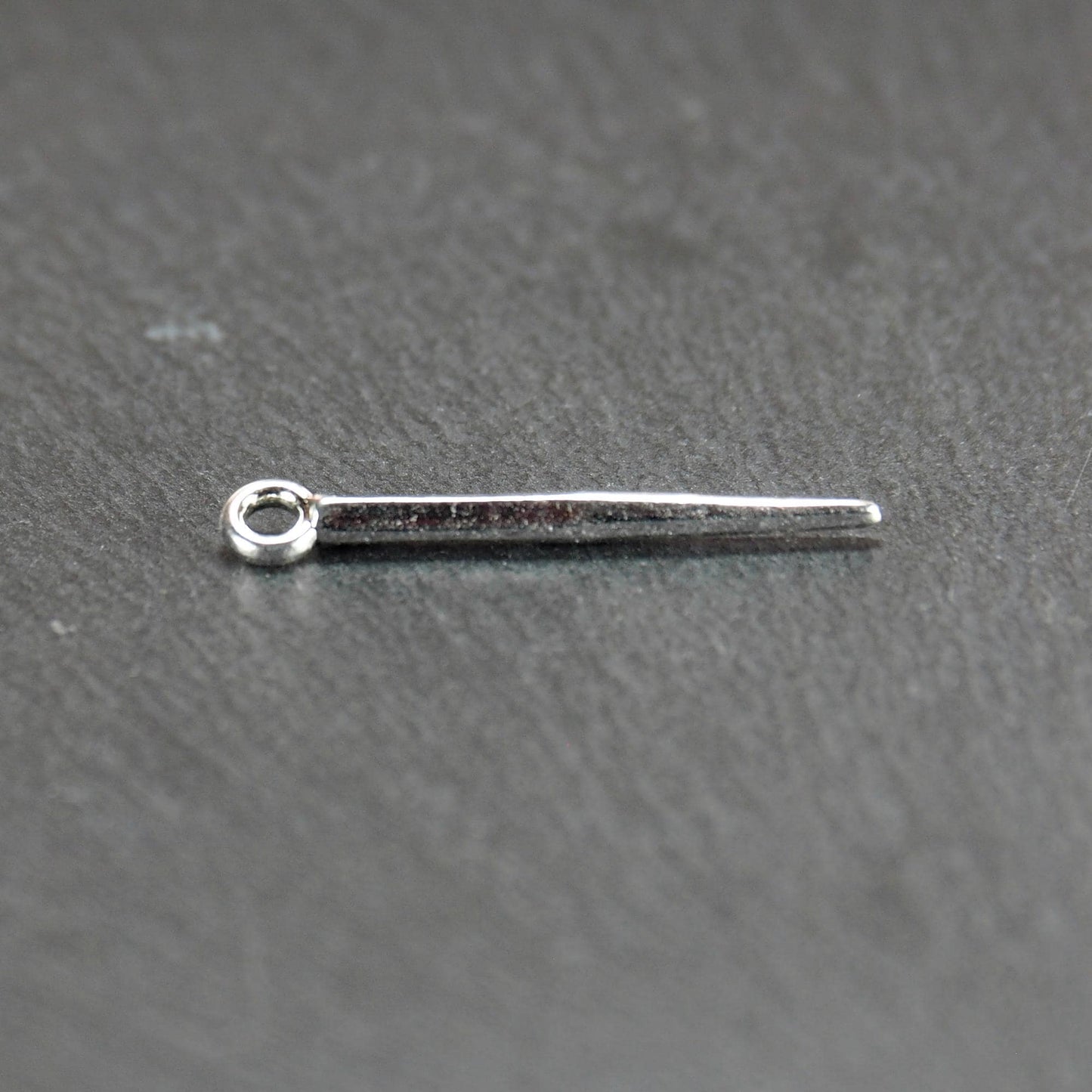 Kegelanhänger aus silberfarbenem Metall, konisch spitz zulaufend mit quadratischem Querschnitt, glatte glänzende Oberfläche und rundes Ösenauge.