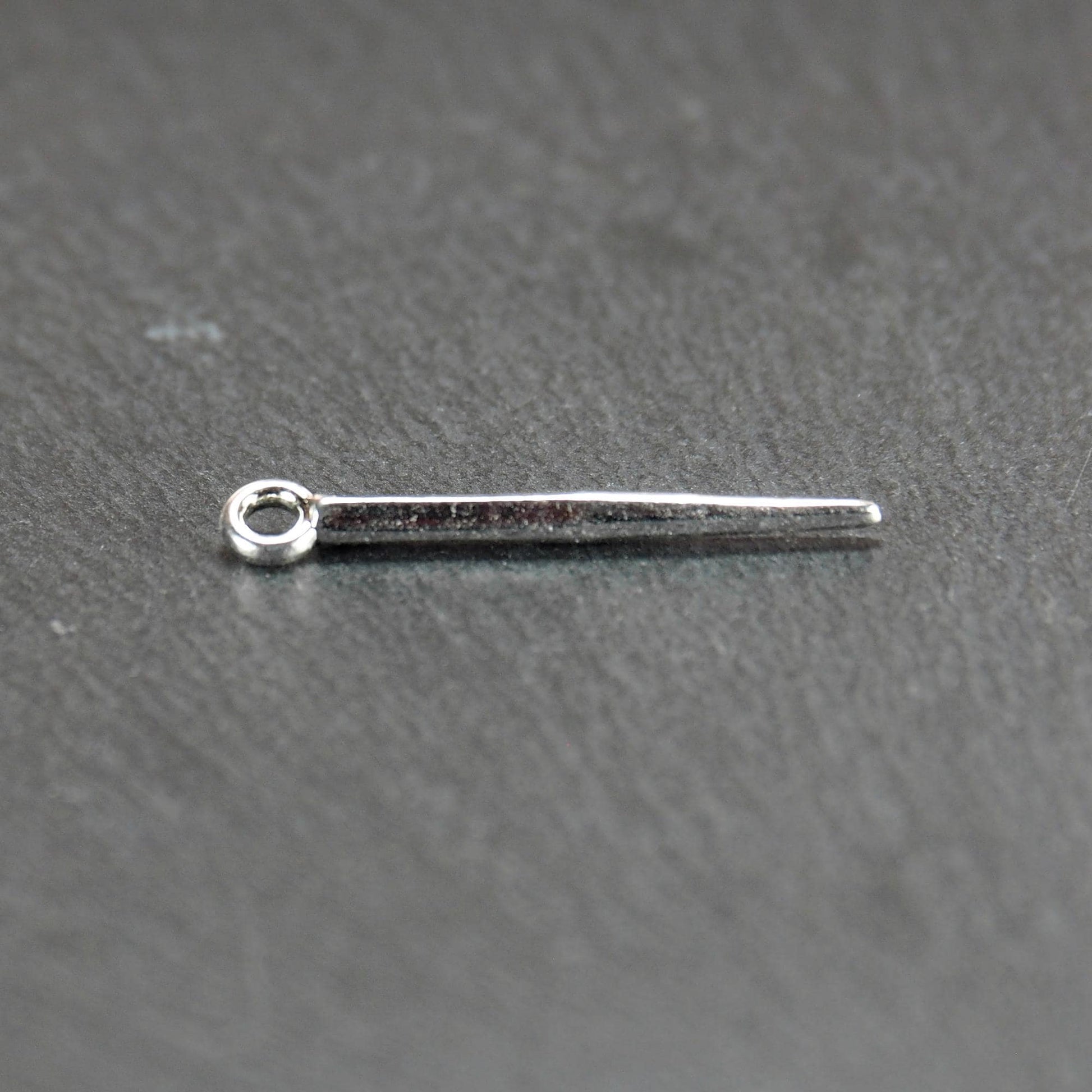 Kegelanhänger aus silberfarbenem Metall, konisch spitz zulaufend mit quadratischem Querschnitt, glatte glänzende Oberfläche und rundes Ösenauge.