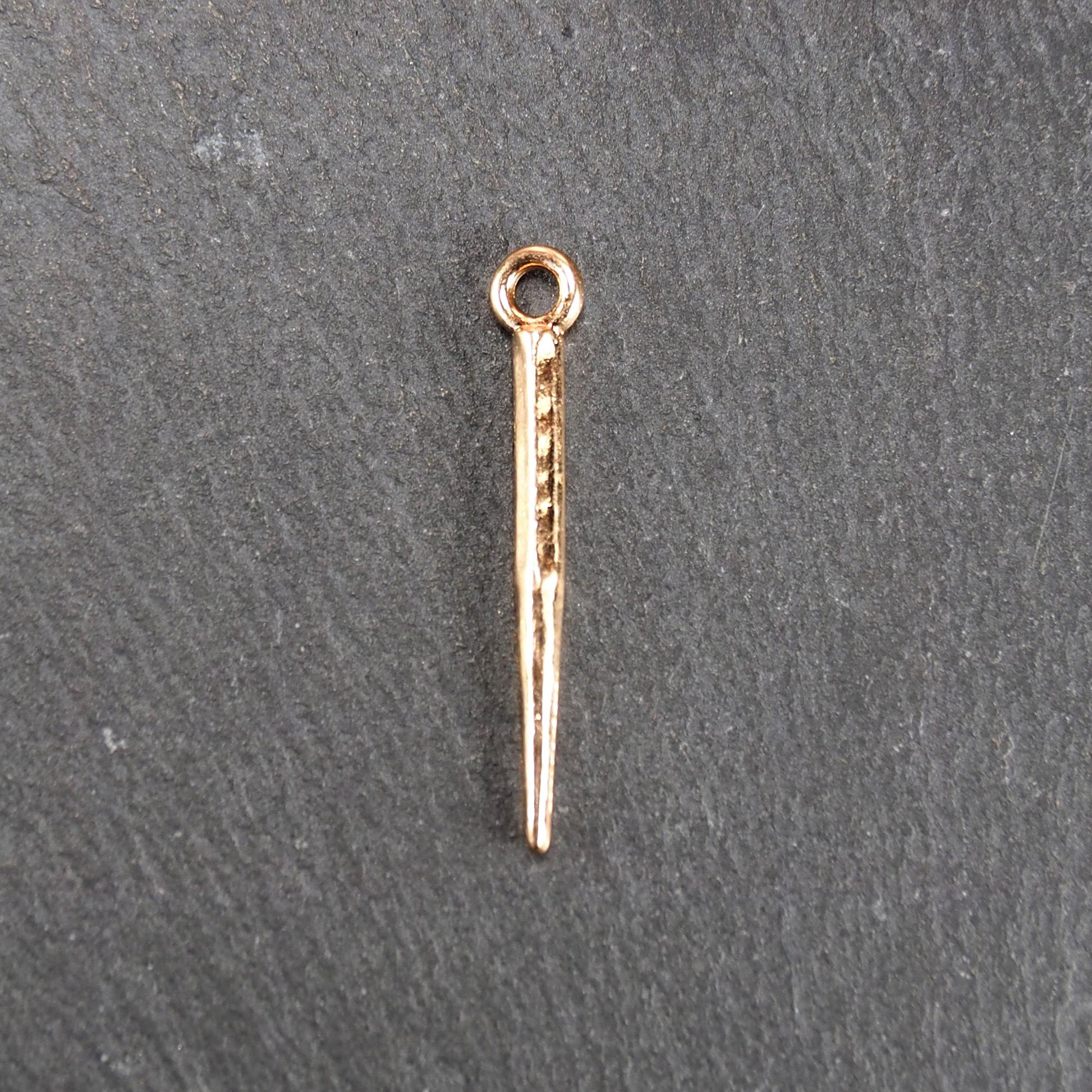 Konischer goldfarbener Anhänger mit glänzender Oberfläche, viereckigem, spitz zulaufendem Schaft und sichtbarer Öse.
