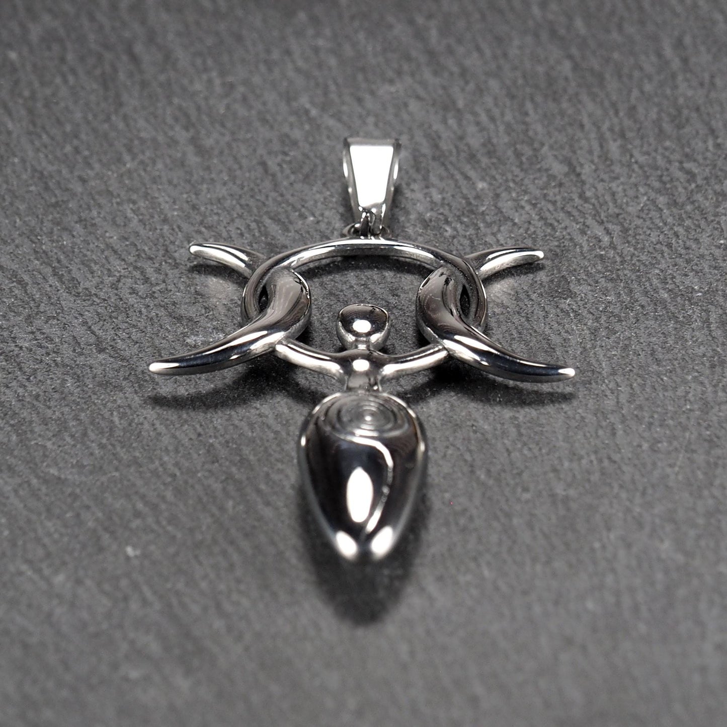 Anhänger aus poliertem silberfarbenem Edelstahl in figürlicher Form mit durchbrochenem Dreifachmond-Motiv, Spirale und Anhängerschlaufe.