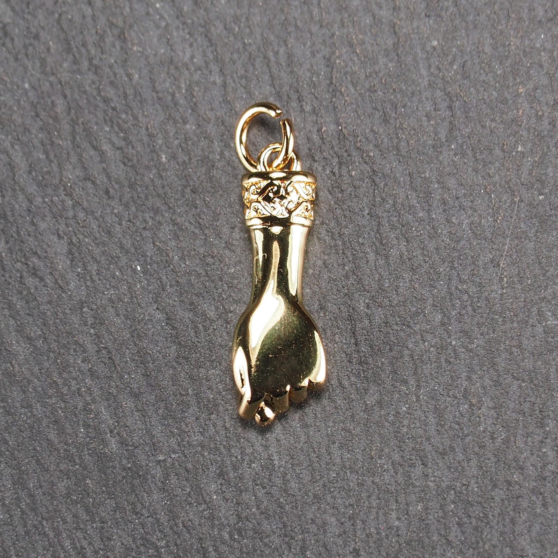 Goldfarbener Anhänger in Figa-Hand-Form mit glänzender Oberfläche, fein gravierter ornamentaler Manschette und kleiner Anhängeröse.