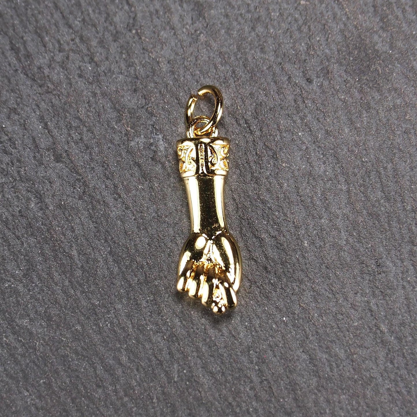 Goldfarbener Anhänger in Figa-Hand-Form mit glänzender Oberfläche, fein gravierter ornamentaler Manschette und kleiner Anhängeröse.