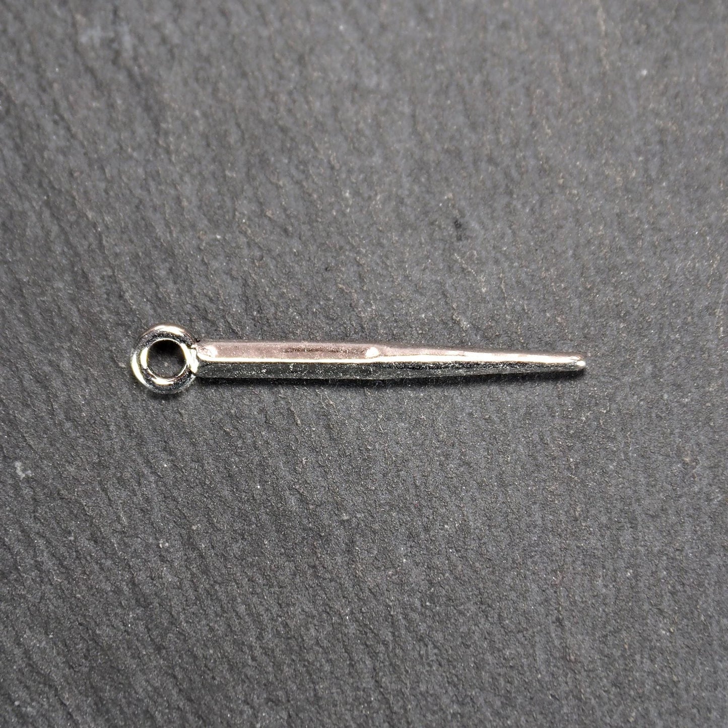 Kegelanhänger aus silberfarbenem Metall, konisch spitz zulaufend mit quadratischem Querschnitt, glatte glänzende Oberfläche und rundes Ösenauge.