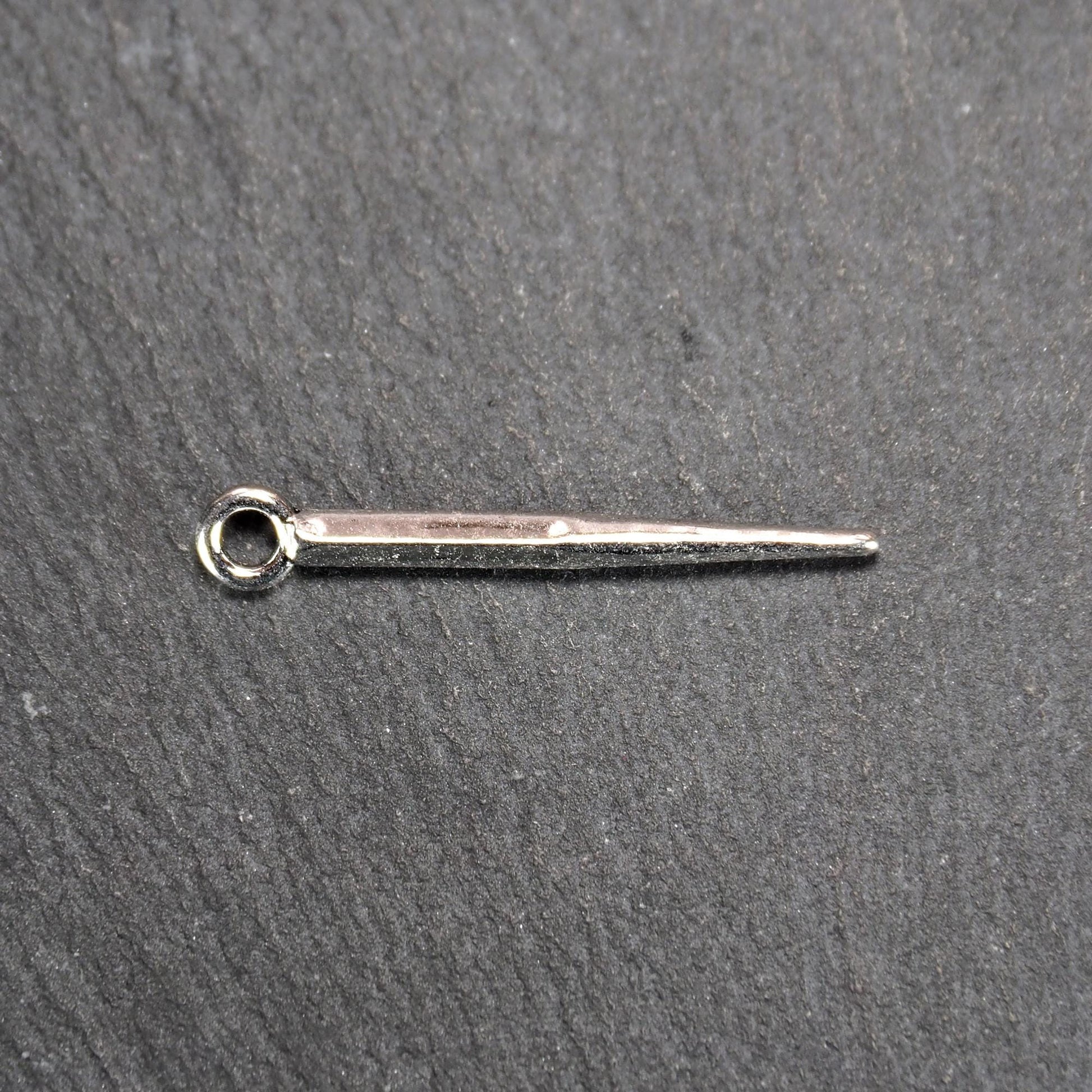 Kegelanhänger aus silberfarbenem Metall, konisch spitz zulaufend mit quadratischem Querschnitt, glatte glänzende Oberfläche und rundes Ösenauge.