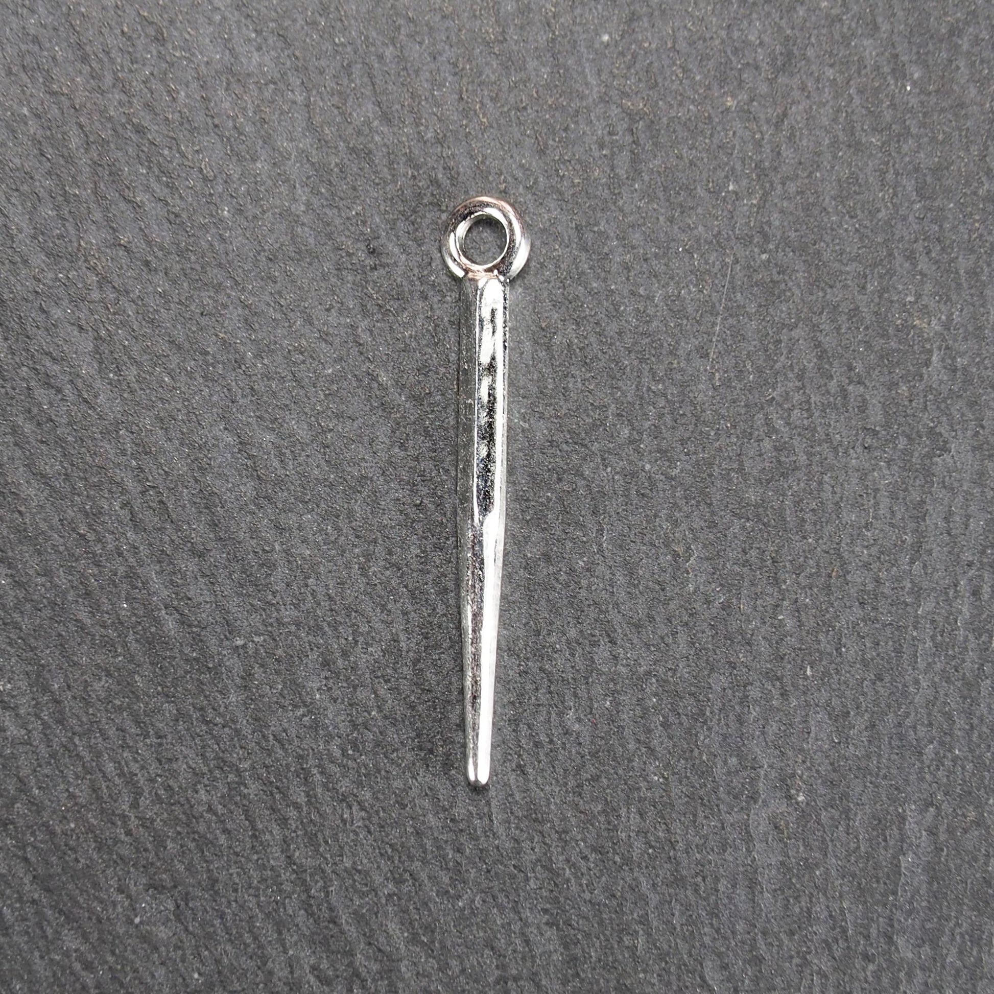 Kegelanhänger aus silberfarbenem Metall, konisch spitz zulaufend mit quadratischem Querschnitt, glatte glänzende Oberfläche und rundes Ösenauge.