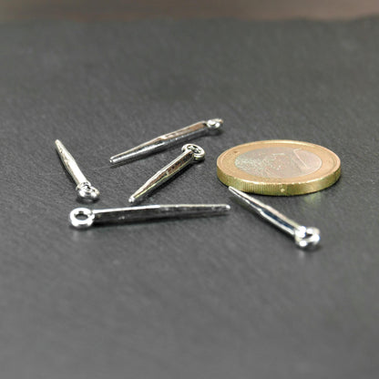 Konischer, silbern glänzender Anhänger mit spitz zulaufender, leicht vierkantiger Form und kleiner Öse, neben einer 1-Euro-Münze zur Größenangabe.