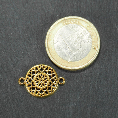 Runder goldfarbener Verbinder mit radialem Mandala-Blütenmuster und zwei Ösen; daneben 1-Euro-Münze als Größenvergleich.