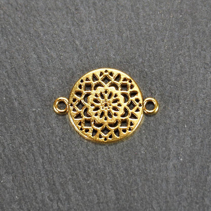 Runder goldfarbener Verbinder mit durchbrochenem, radial-symmetrischem Mandala-/Blütenmuster und zwei gegenüberliegenden Ösen.