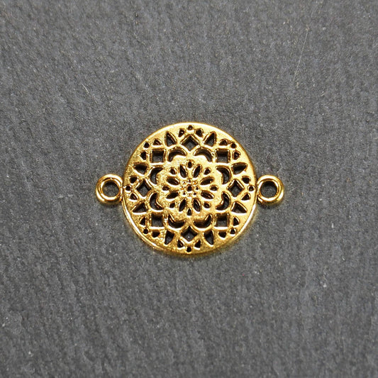 Runder goldfarbener Verbinder mit durchbrochenem, radial-symmetrischem Mandala-/Blütenmuster und zwei gegenüberliegenden Ösen.