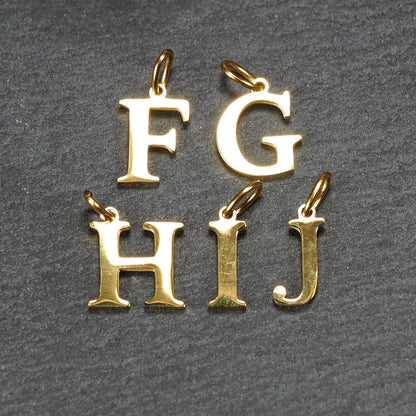 Fünf goldfarbene, glänzende Großbuchstaben (F, G, H, I, J) als serifenbetonte Anhänger mit kleinen Ösen.