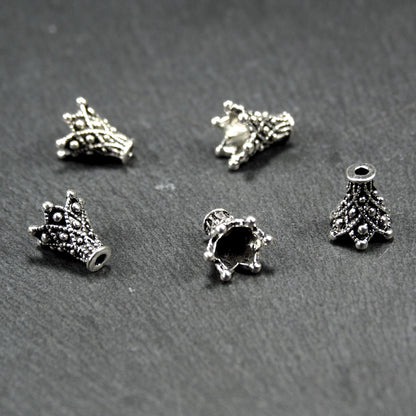 Konische, antik-silberne Perlenkappe mit durchbrochenem filigranem Ornament, reliefartigen Kugeln und sichtbarem Fädelloch oben.