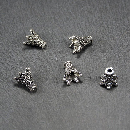 Konische, antik-silberne Perlenkappe mit durchbrochenem filigranem Ornament, reliefartigen Kugeln und sichtbarem Fädelloch oben.