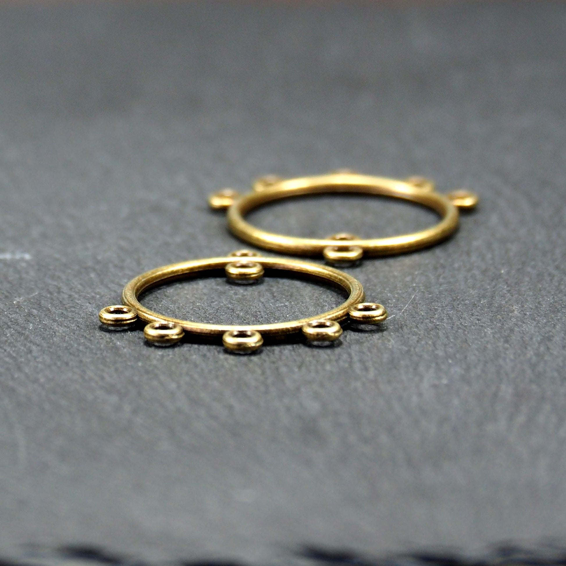 Zwei runde Chandelier-Verbinder aus antik bronzefarbenem Metall, je mit einer oberen Öse und fünf gleichmäßig angeordneten unteren Ösen.