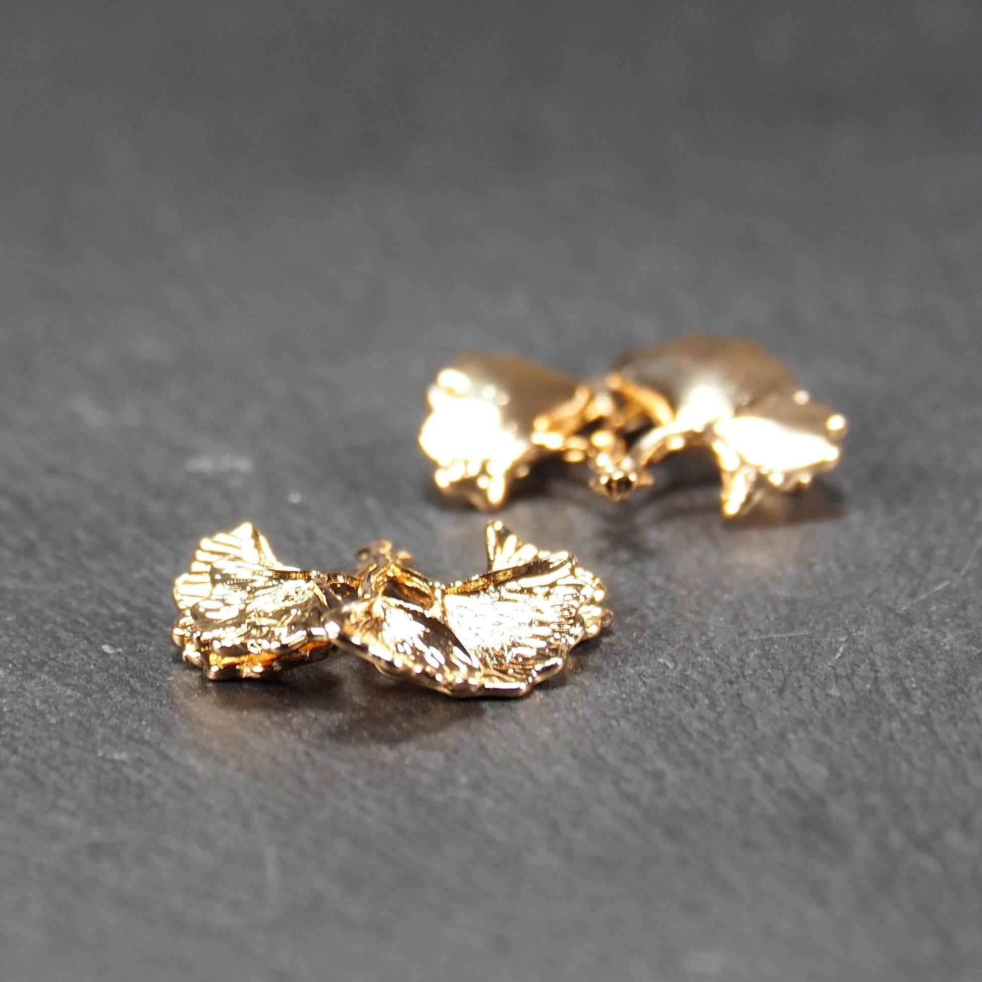 Anhänger, vergoldet und glänzend, in Form dreigeteilter Ginkgo-Blätter mit reliefartiger Struktur und sichtbaren Blattadern, oben kleine Öse.