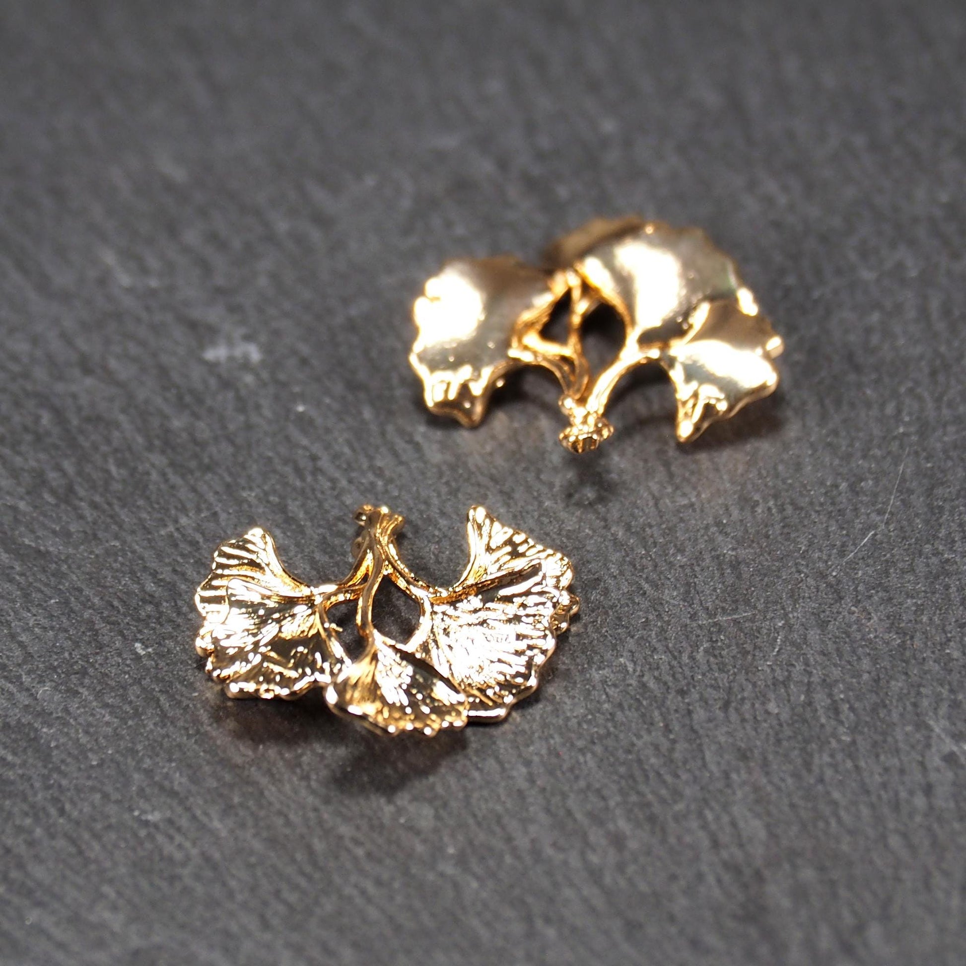 Anhänger, vergoldet und glänzend, in Form dreigeteilter Ginkgo-Blätter mit reliefartiger Struktur und sichtbaren Blattadern, oben kleine Öse.