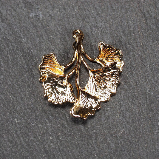 Anhänger, vergoldet und glänzend, in Form dreigeteilter Ginkgo-Blätter mit reliefartiger Struktur und sichtbaren Blattadern, oben kleine Öse.