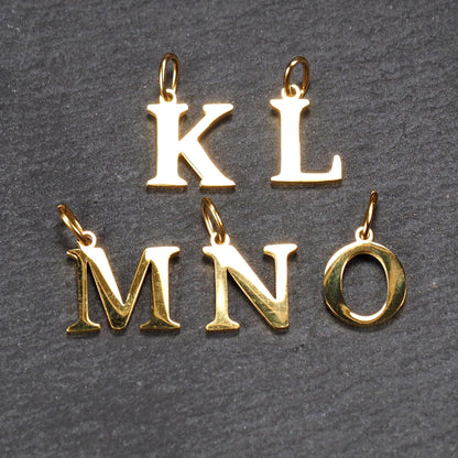 Fünf goldfarbene, glänzende Versal-Serifen-Buchstabenanhänger (K, L, M, N, O) mit kleinen Ösen.