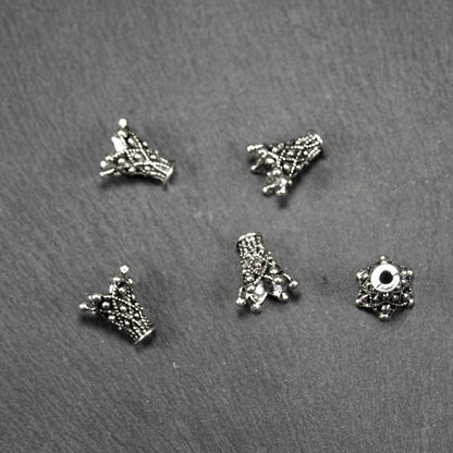 Konische, antik-silberne Perlenkappe mit durchbrochenem filigranem Ornament, reliefartigen Kugeln und sichtbarem Fädelloch oben.