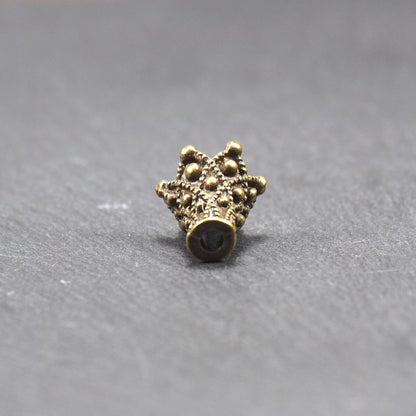 Konische bronzefarbene Perlenkappe aus Metall mit filigranem Ornamentreliéf, kugeligen Verzierungen und zentralem Fädelloch.