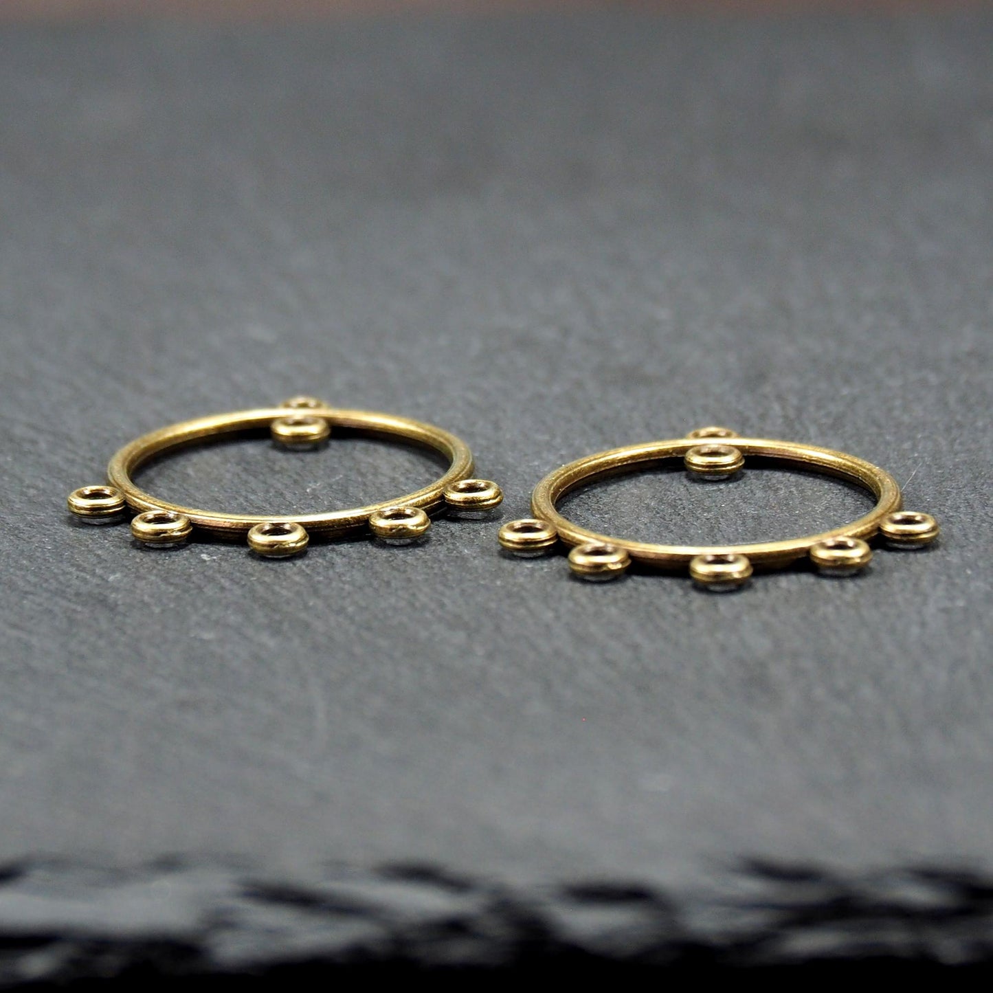 Zwei runde Chandelier-Verbinder aus antik bronzefarbenem Metall, je mit einer oberen Öse und fünf gleichmäßig angeordneten unteren Ösen.