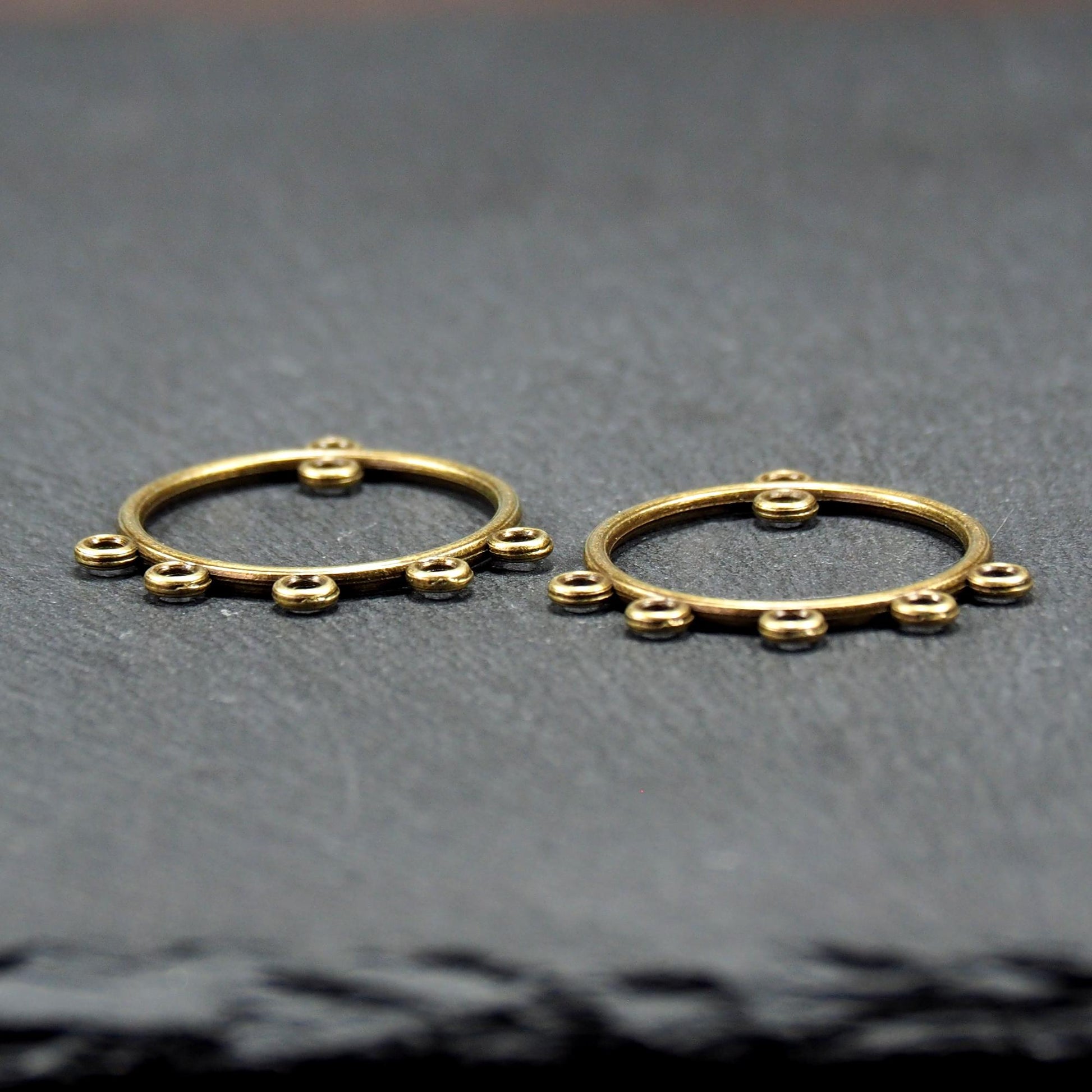 Zwei runde Chandelier-Verbinder aus antik bronzefarbenem Metall, je mit einer oberen Öse und fünf gleichmäßig angeordneten unteren Ösen.