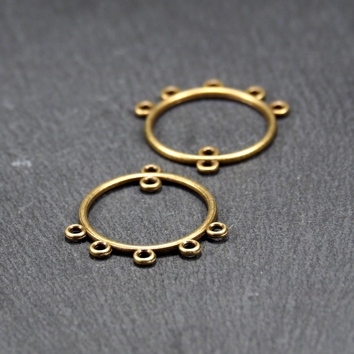 Zwei runde Chandelier-Verbinder aus antik bronzefarbenem Metall, je mit einer oberen Öse und fünf gleichmäßig angeordneten unteren Ösen.