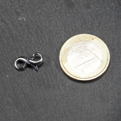 Ein doppelseitiger Karabiner im liegenden Acht-Design, silberfarben glänzend mit organisch geschwungener, durchbrochener Form und integrierter Öse.