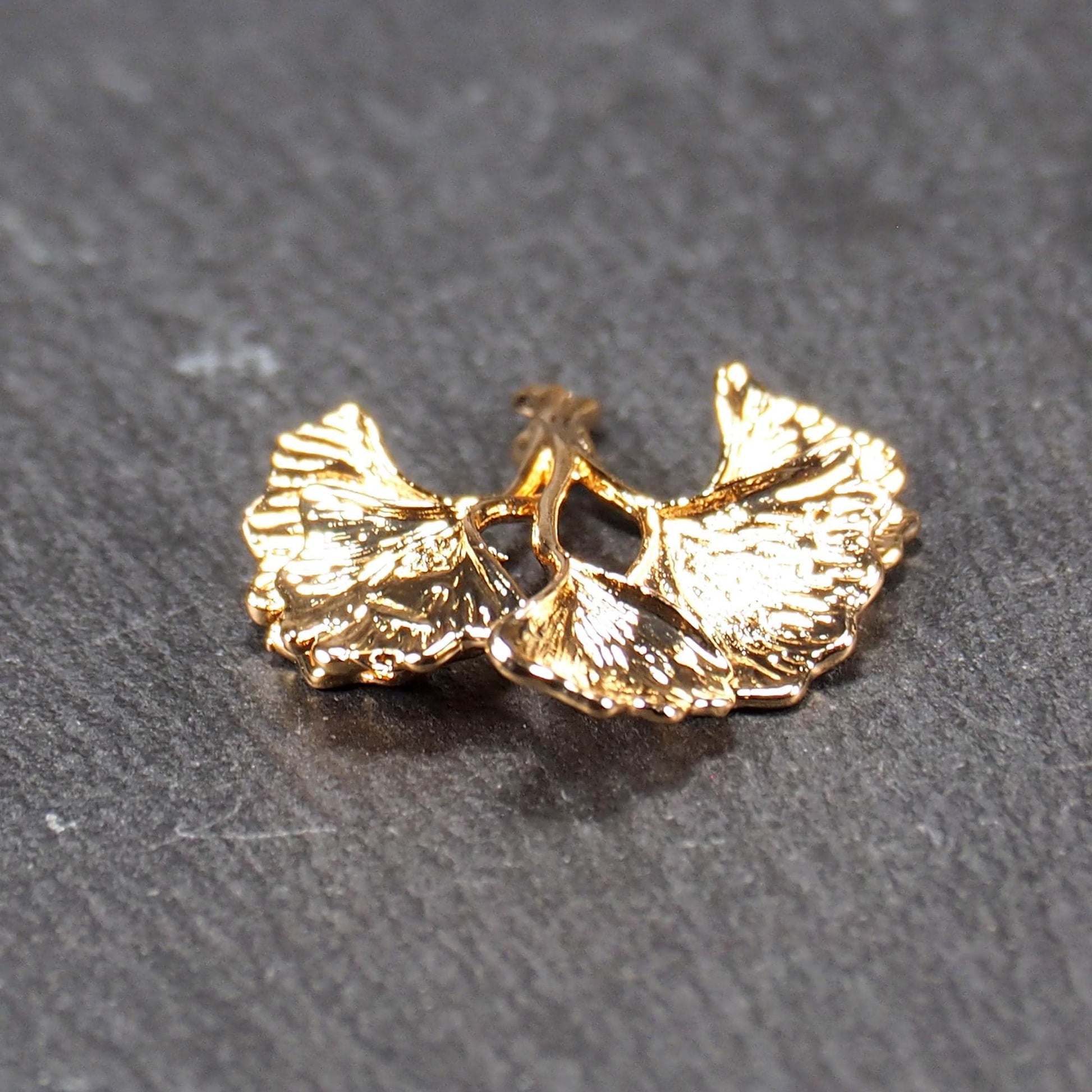 Anhänger, vergoldet und glänzend, in Form dreigeteilter Ginkgo-Blätter mit reliefartiger Struktur und sichtbaren Blattadern, oben kleine Öse.