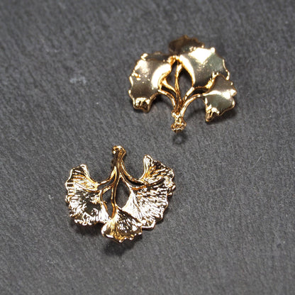 Anhänger, vergoldet und glänzend, in Form dreigeteilter Ginkgo-Blätter mit reliefartiger Struktur und sichtbaren Blattadern, oben kleine Öse.