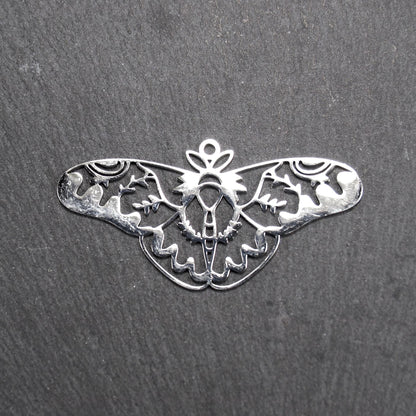 Anhänger / Verbinder in Mottenform aus poliertem silberfarbenem Edelstahl, filigranes durchbrochenes Ornament-Flügeldesign mit integrierter Öse oben.