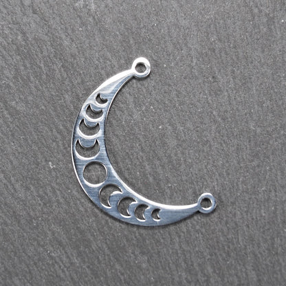 Sichelförmiger silberner Metallverbinder mit ausgeschnittenem Mondphasen-Motiv und je einer Rundöse an den Enden.
