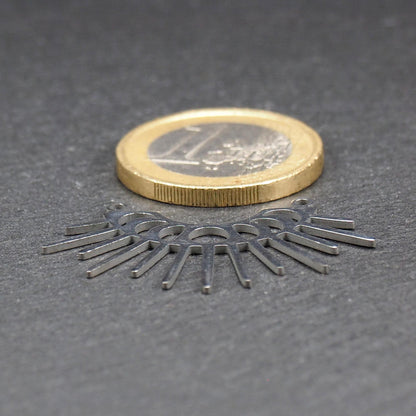 Versilberter Metallverbinder, halbkreisförmig und durchbrochen, mit rundem Mittelloch, mehreren schmalen radialen Strahlen, glänzender Oberfläche und zwei kleinen Ösen oben.
