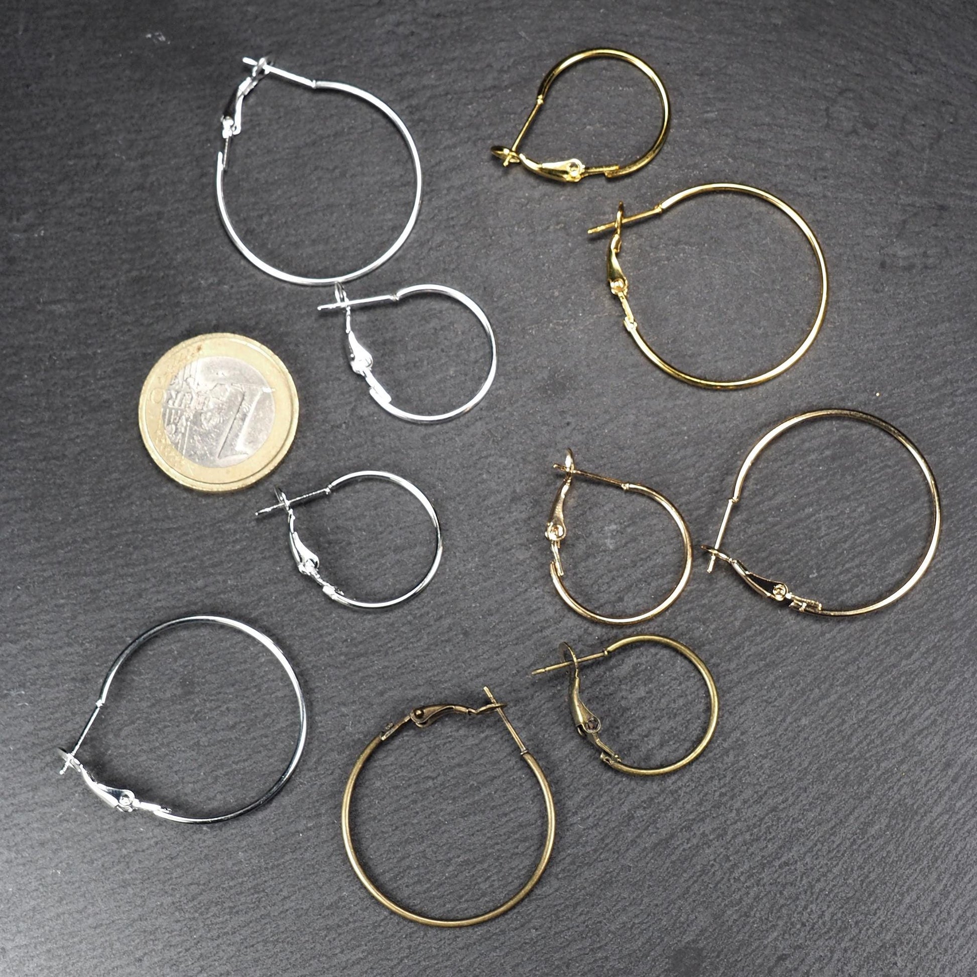 Runde Klapp-Creolen in silber, platin, hellgold, gelbgold und bronze mit Klappverschluss und glatter, glänzender Oberfläche, jeweils in zwei Größen. Mit 1 Euro Münze zum Größenvergleich.