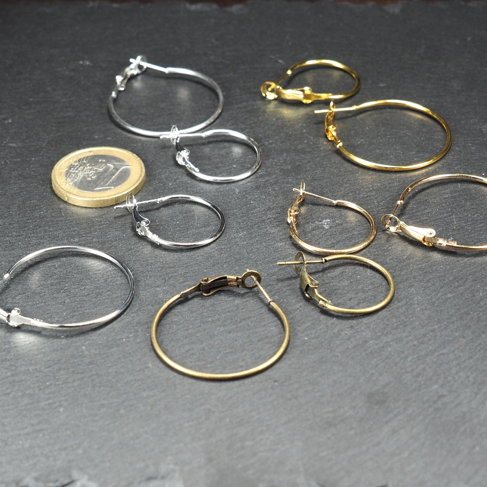 Runde Klapp-Creolen in silber, platin, hellgold, gelbgold und bronze mit Klappverschluss und glatter, glänzender Oberfläche, jeweils in zwei Größen. Mit 1 Euro Münze zum Größenvergleich.
