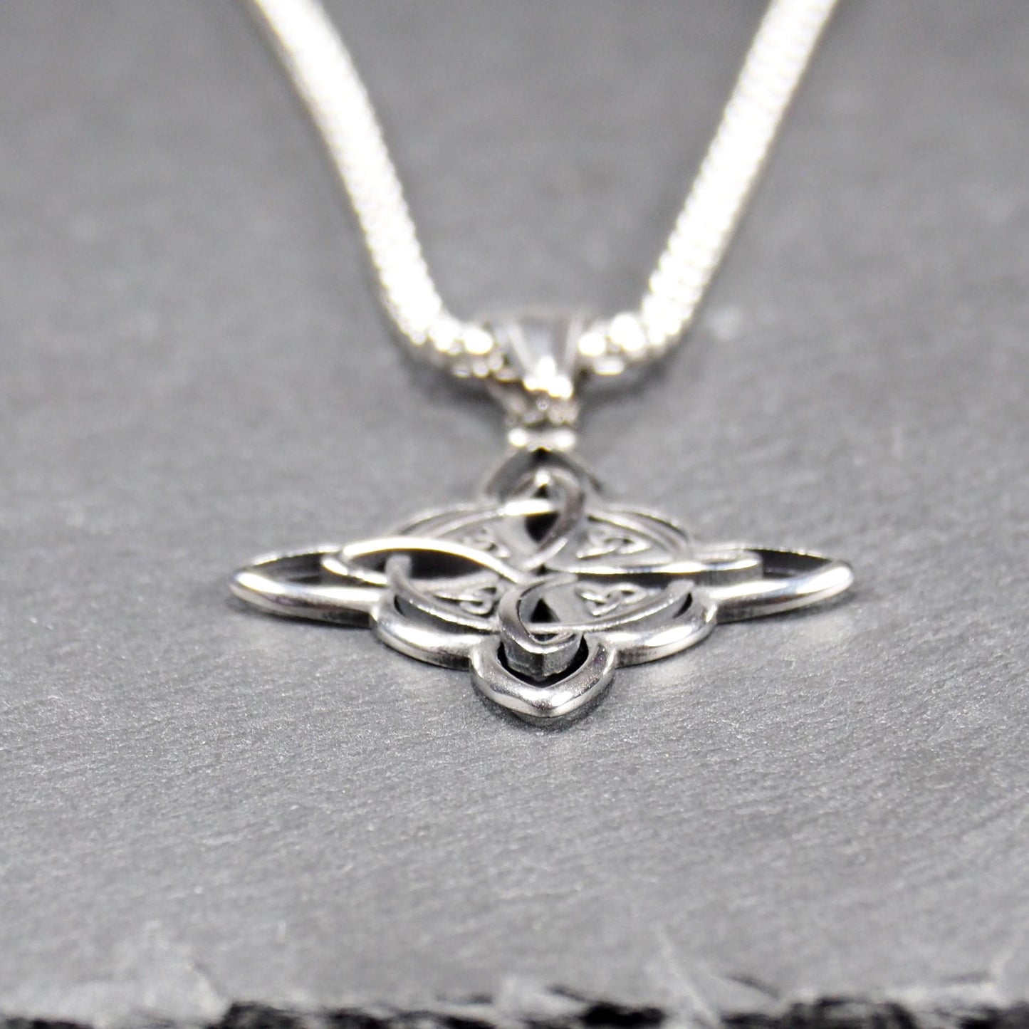 Keltischer, vierblättriger, durchbrochener Anhänger in silberner, glänzender Optik an einer quadratischen Boxkette mit Karabiner.