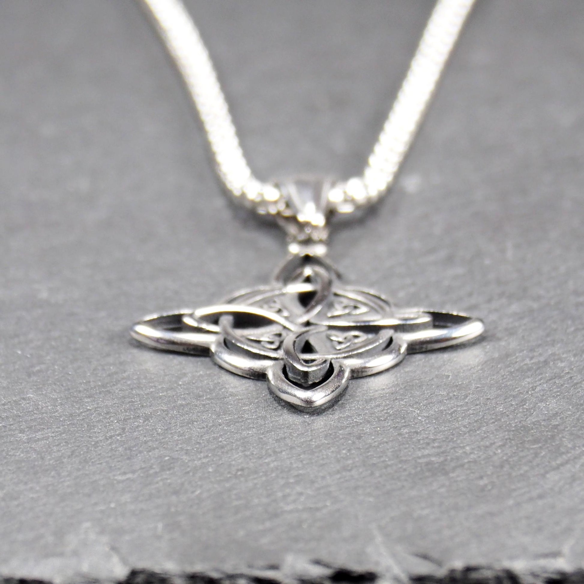 Keltischer, vierblättriger, durchbrochener Anhänger in silberner, glänzender Optik an einer quadratischen Boxkette mit Karabiner.