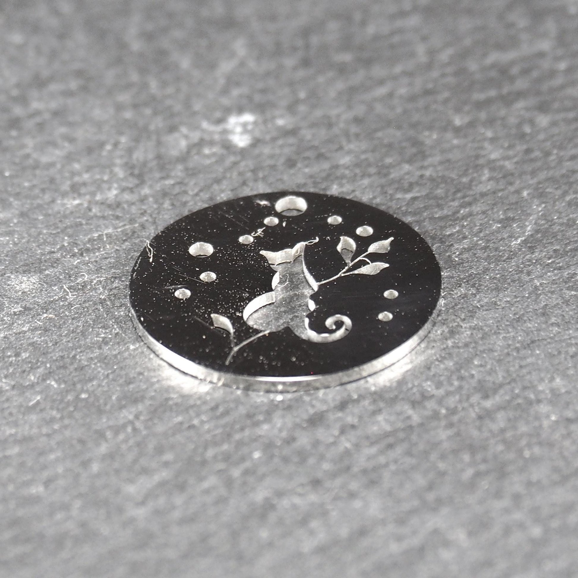 Runder, flacher Anhänger aus poliertem Edelstahl, Cut-out mit sitzender Katzen-Silhouette und Blattzweig, Öse oben und mehrere kleine Bohrungen.