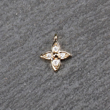 Vierblättriger goldfarbener Blütenanhänger mit zentraler Kugel, vier eingesetzten Zirkonia in den Blattspitzen und oberer Öse.