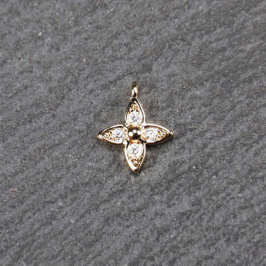 Vierblättriger goldfarbener Blütenanhänger mit zentraler Kugel, vier eingesetzten Zirkonia in den Blattspitzen und oberer Öse.