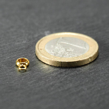 Anhängeröse, goldfarben und glänzend, ringförmig mit zusätzlicher kleiner Öse, neben einer 1‑Euro‑Münze zur Größendarstellung.